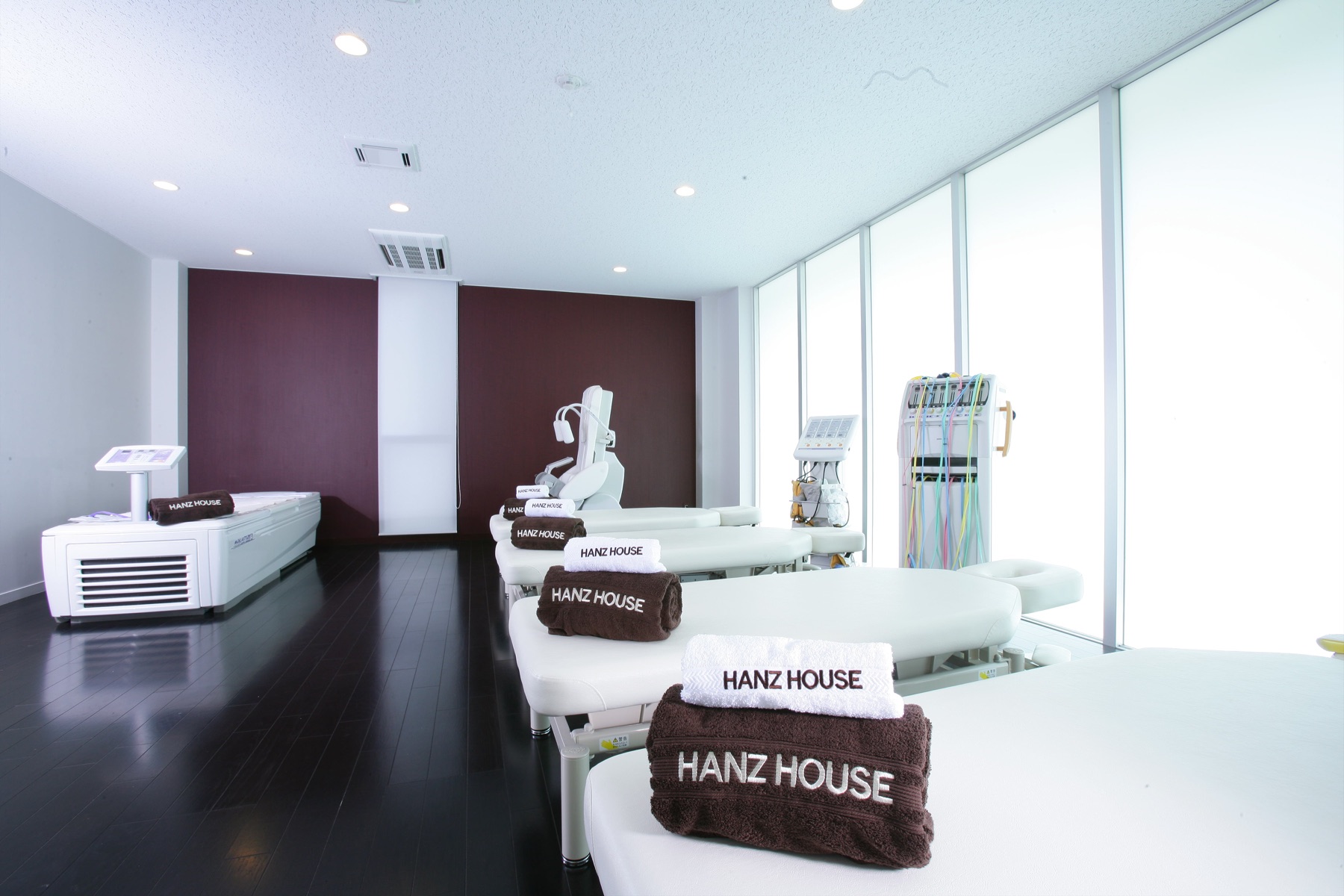 HANZ HOUSE のロゴが入ったタオルが置かれた、白を基調とした施術空間